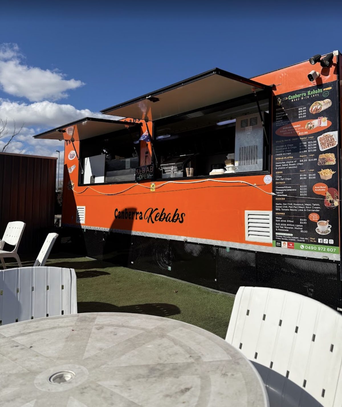 The orange Canberra Kebabs food truck with outdoor tables on the lawn